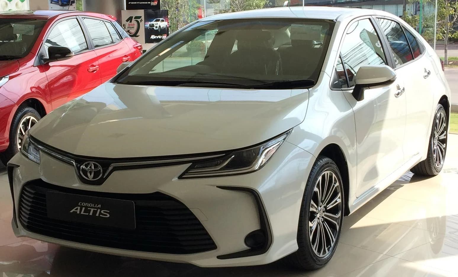 White 2021 Toyota Corolla Altis 1.8 Sport parked in a showroom.
