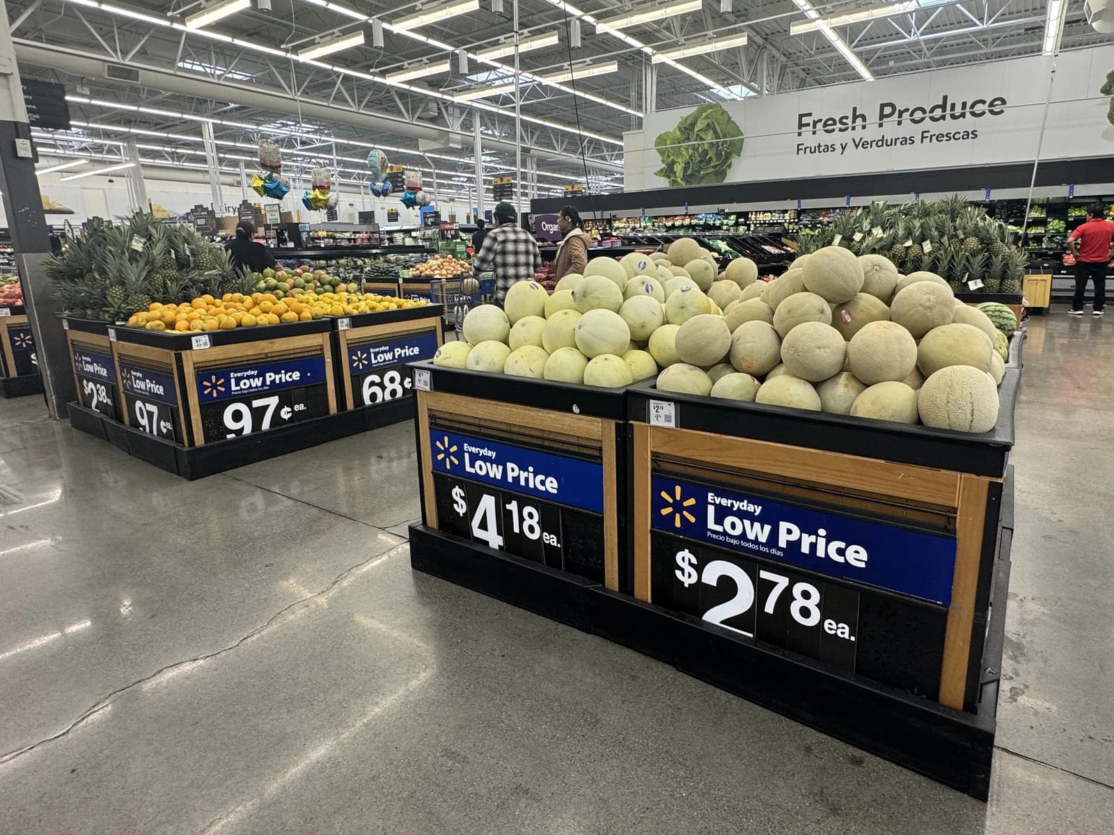 Cantaloupes and other fresh produce displayed in bins at a supermarket.