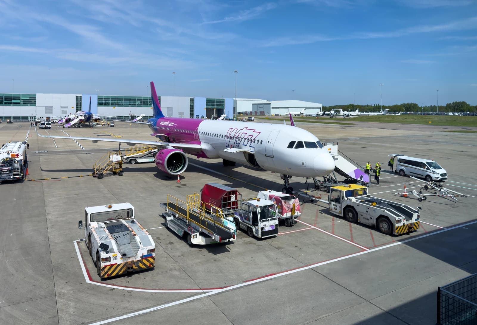 A purple and white Wizz Air UK Airbus A321neo aircraft parked at London Luton Airport.