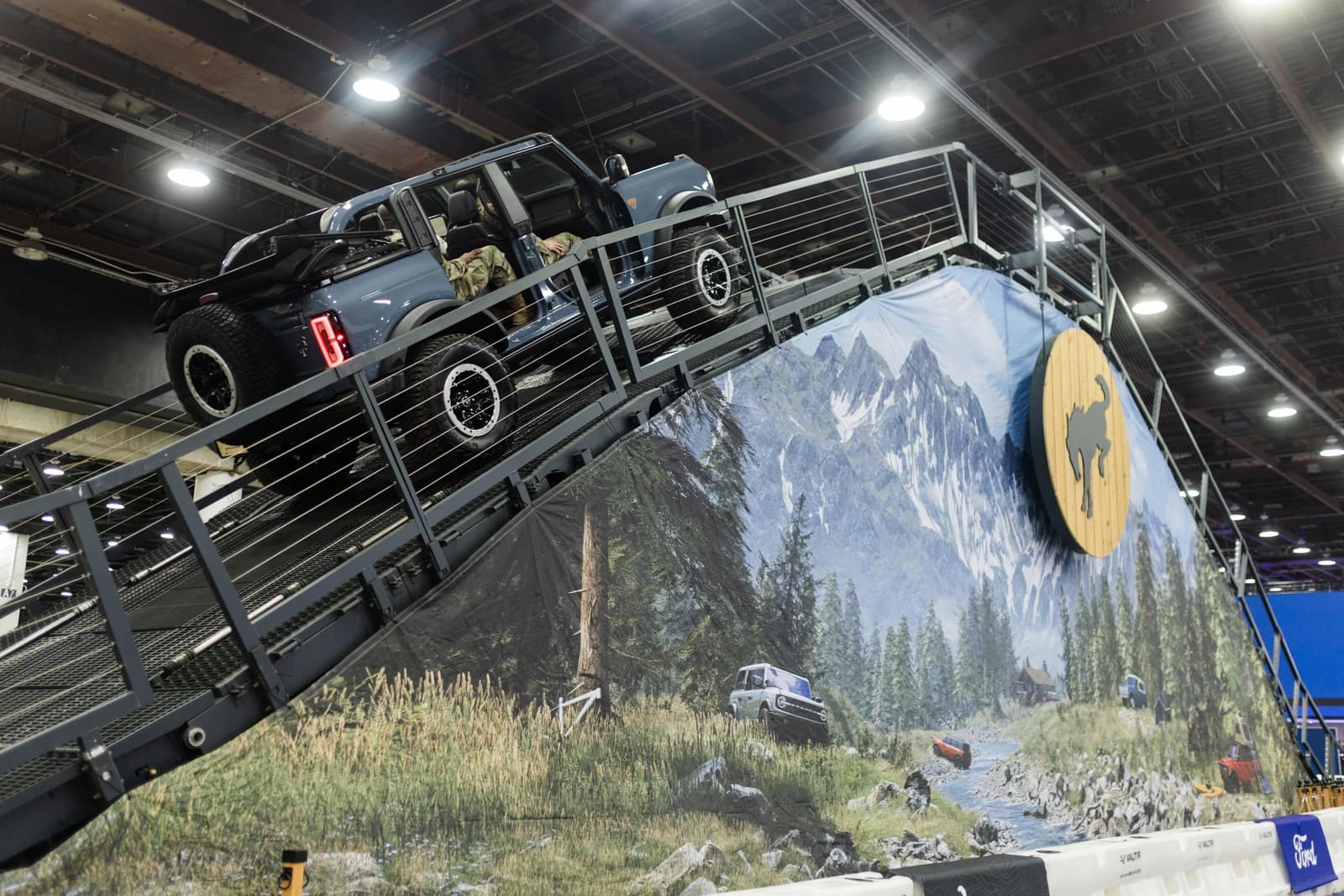 Ford Bronco four-door vehicle driven up a steep metal ramp indoors at an auto show.