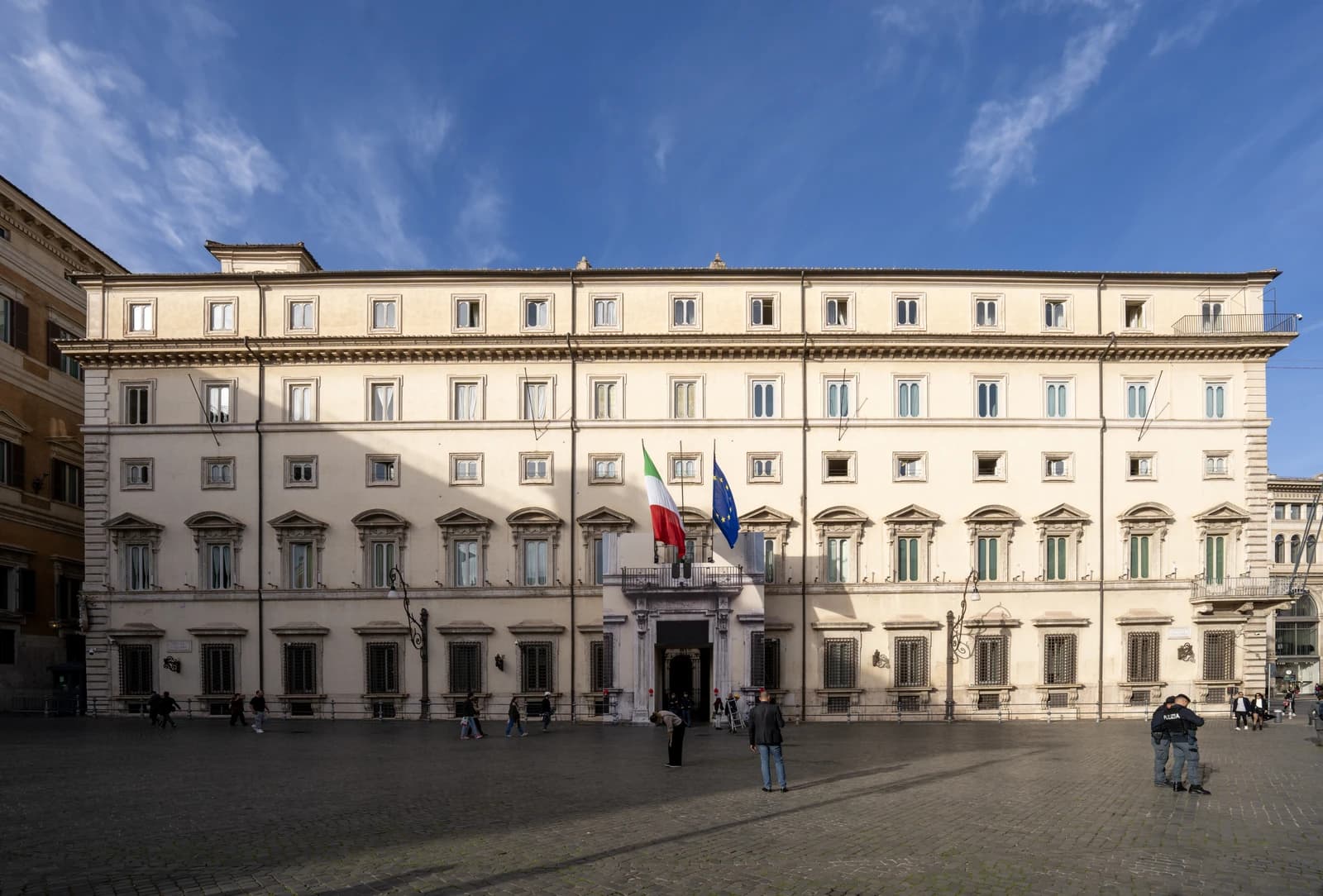 Exterior view of Palazzo Chigi in Rome, displaying Italian and European Union flags.