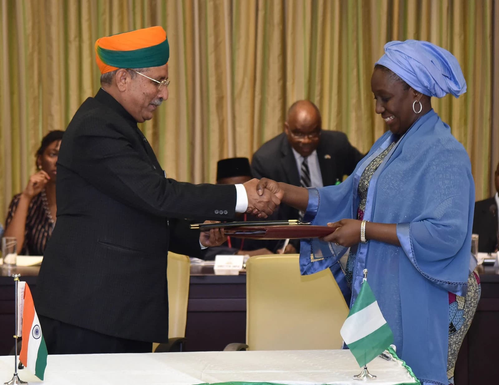 Arjun Ram Meghwal and Nigerian Minister Aisha Abubakar exchange documents and shake hands.