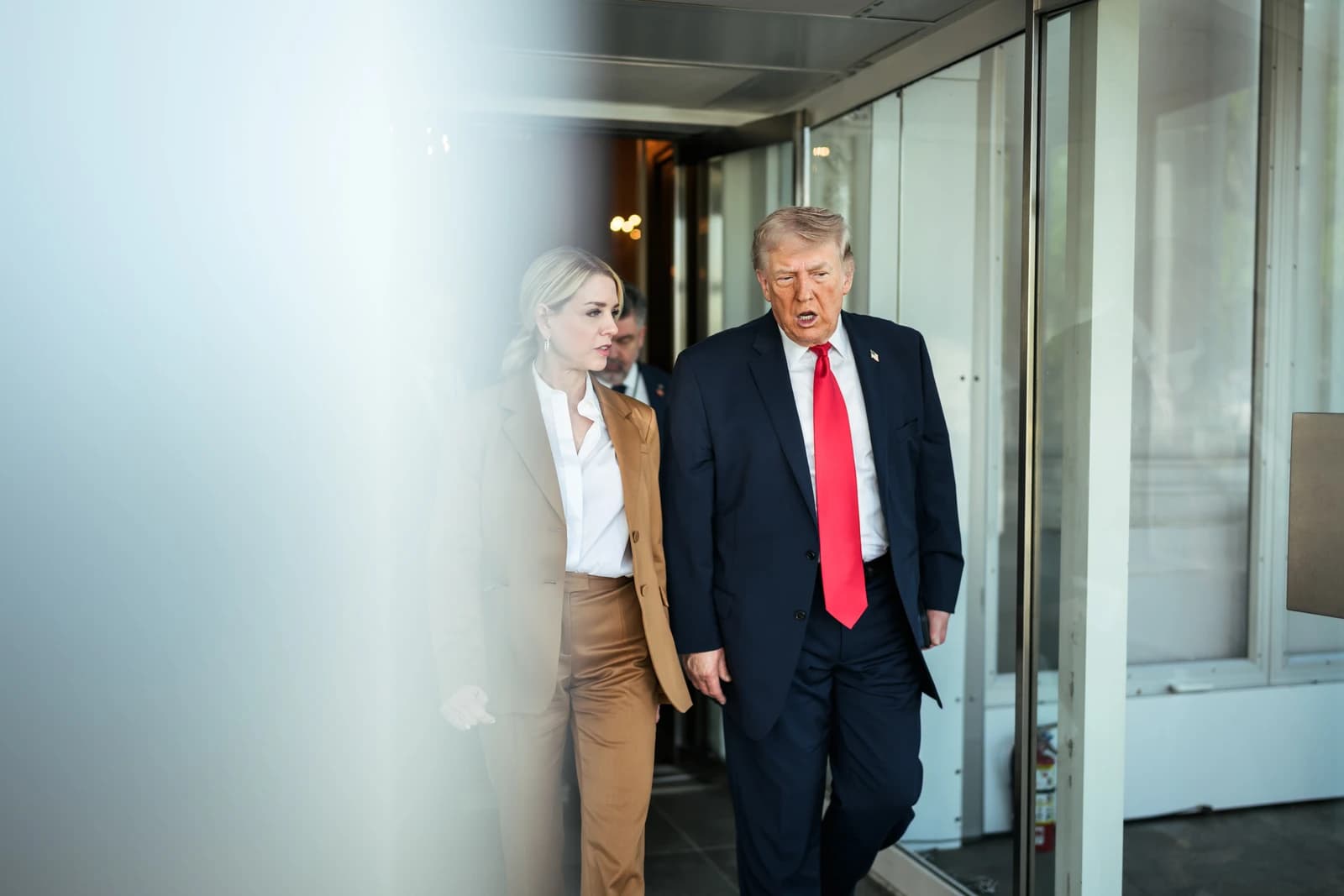 Donald Trump walking with a woman at the Supreme Court building entrance.