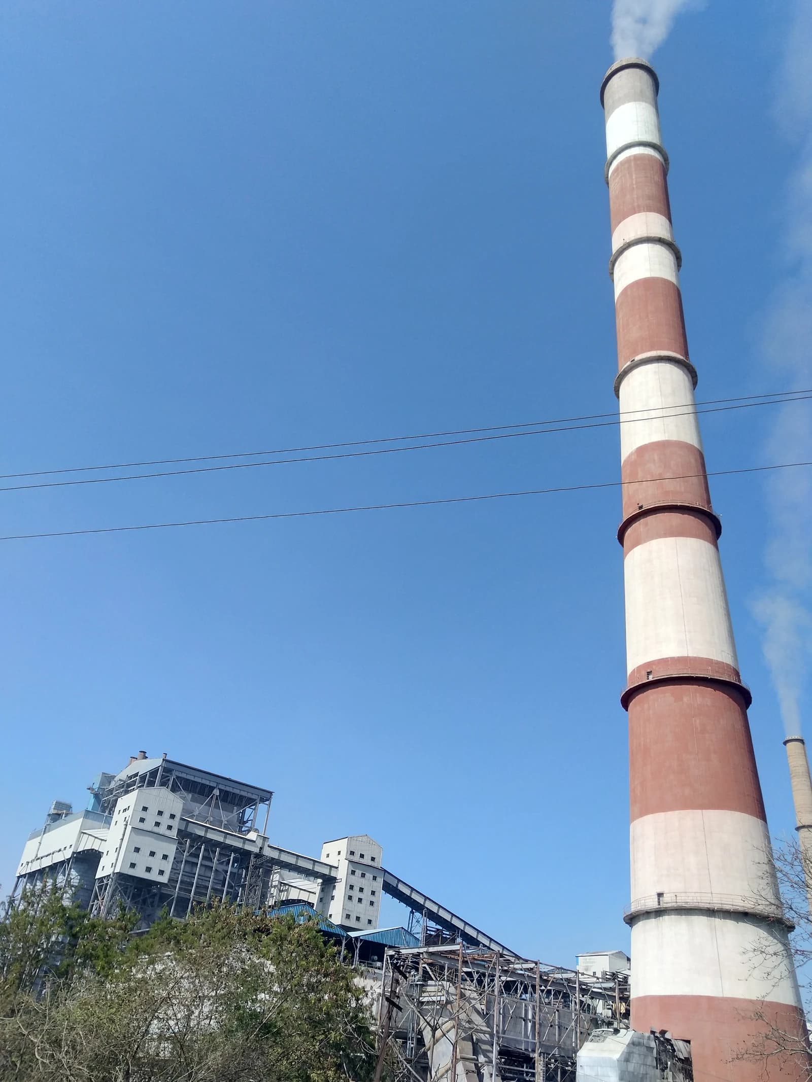 CSEB Thermal Power Plant chimney emitting smoke against a clear blue sky.