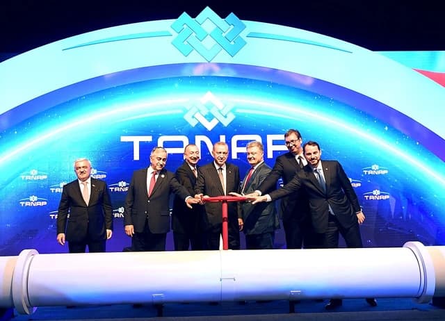 Turkish President Erdogan and other leaders turn a red valve on a white pipeline.
