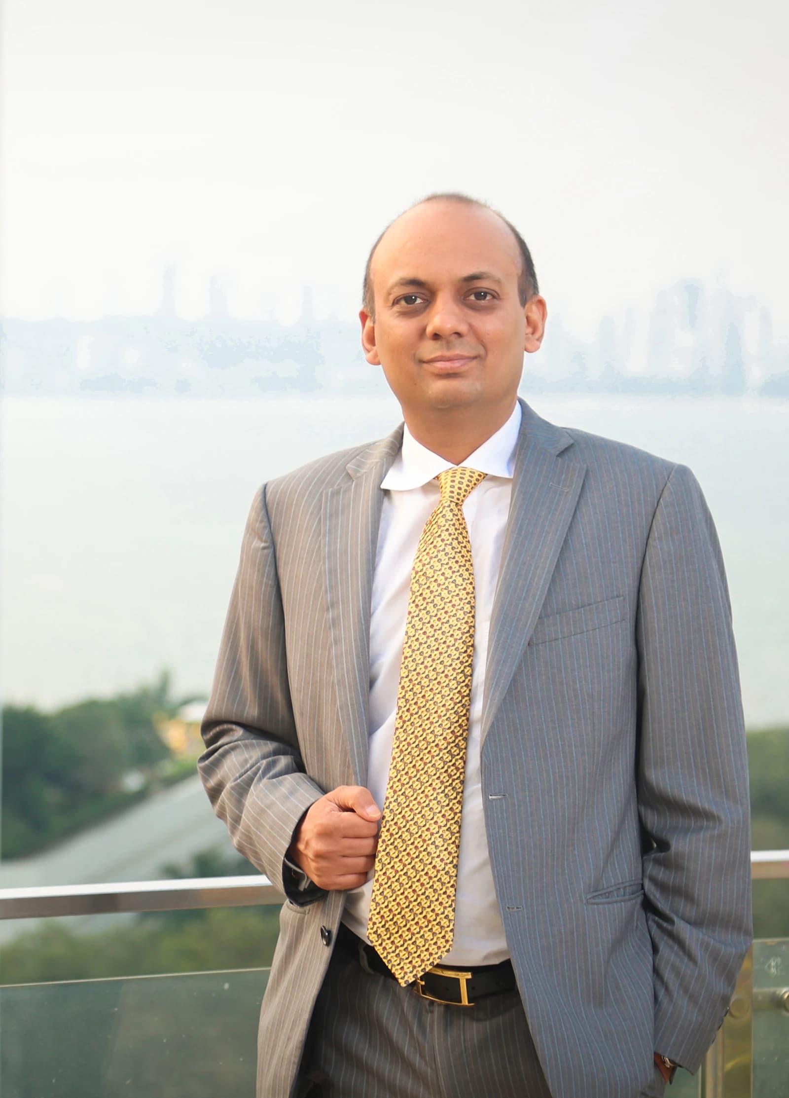 Mr. Kushagra Bajaj, Indian businessman, stands outdoors with a city view.