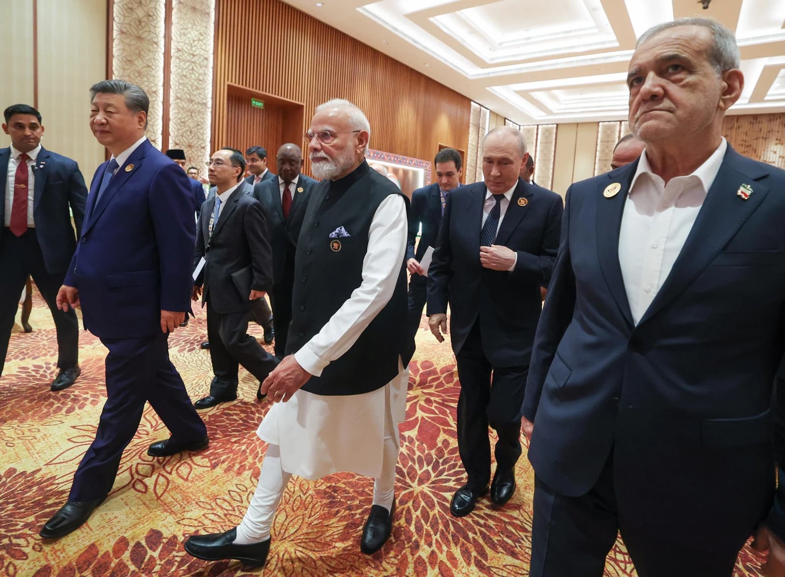 Chinese President Xi Jinping, Indian Prime Minister Narendra Modi, and Russian President Vladimir Putin walking in a hallway.
