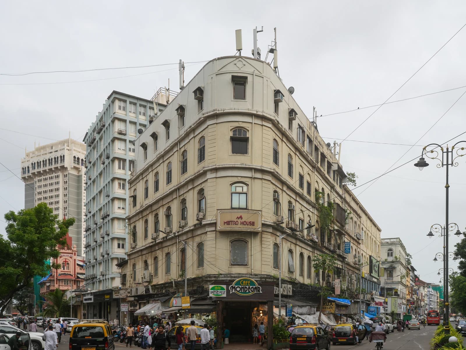 Corner view of Metro House building in Colaba, Mumbai, with street traffic.