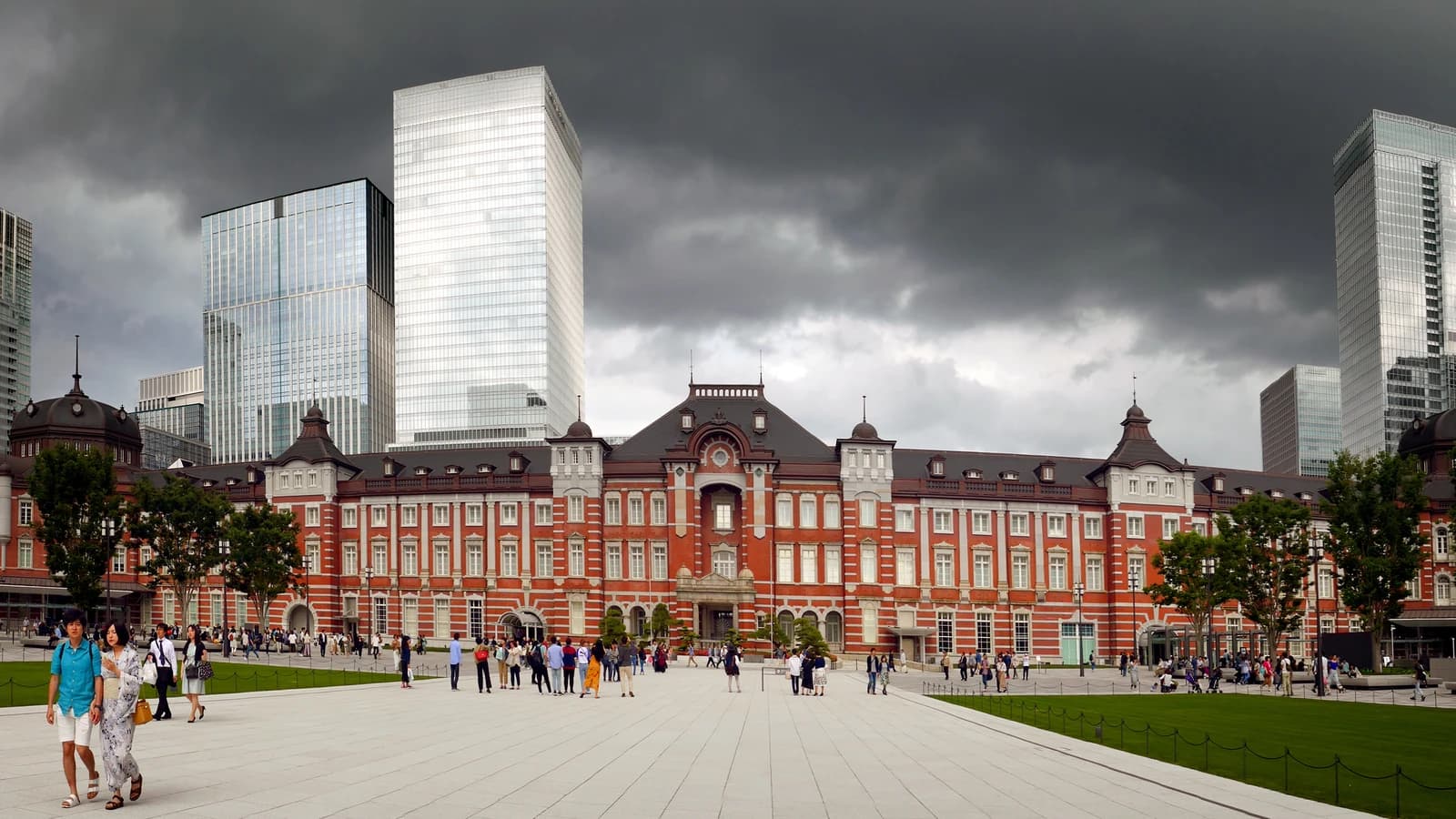 Exterior of Tokyo Station building with traditional red brick architecture and surrounding modern skyscrapers.