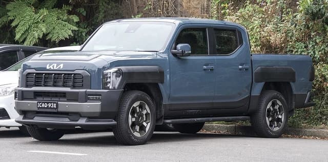 2025 Kia Tasman pickup truck parked on an urban street.