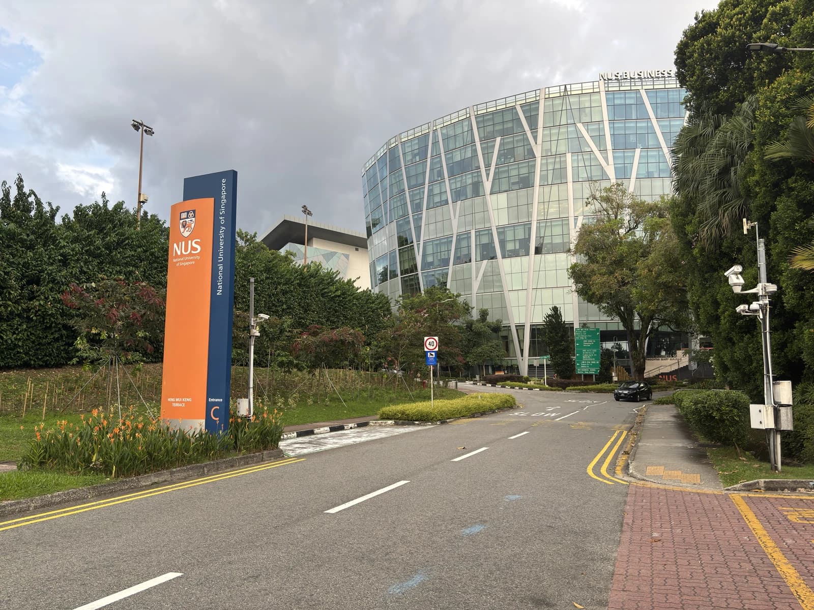Entrance sign for the National University of Singapore campus on a cloudy day.