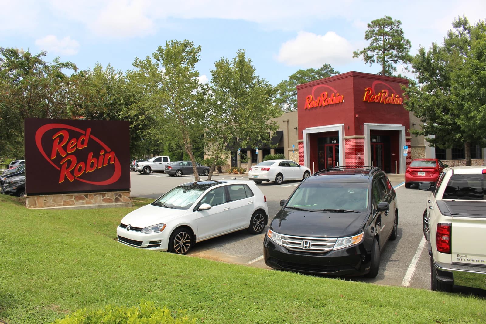 Exterior of a Red Robin restaurant and sign with cars in the parking lot.