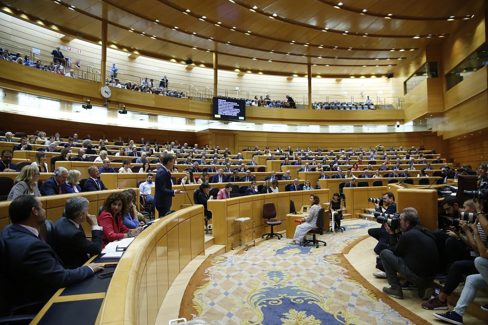 Members of a legislative body listening to a speaker at a parliamentary session.