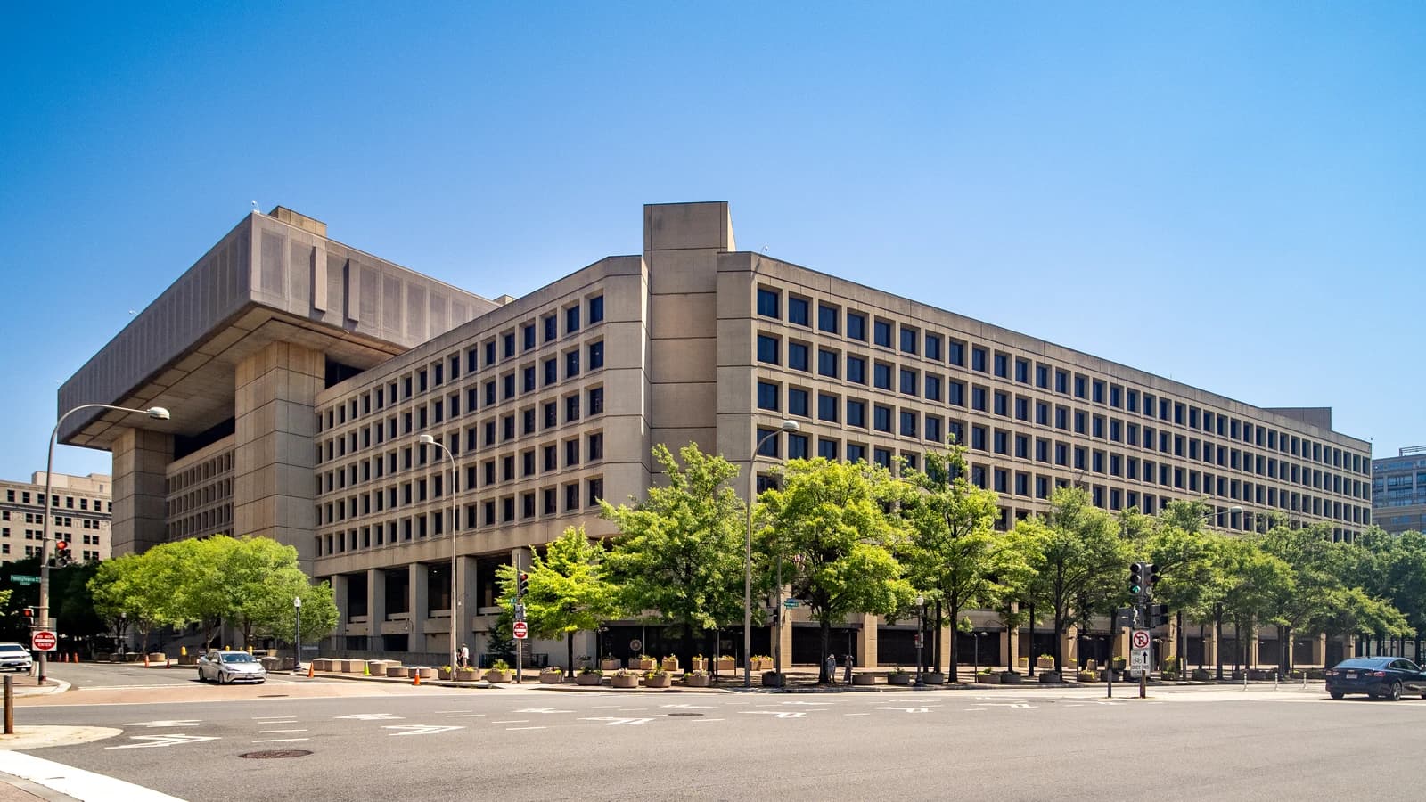 Exterior of the J. Edgar Hoover Building, FBI Headquarters, under a clear blue sky.