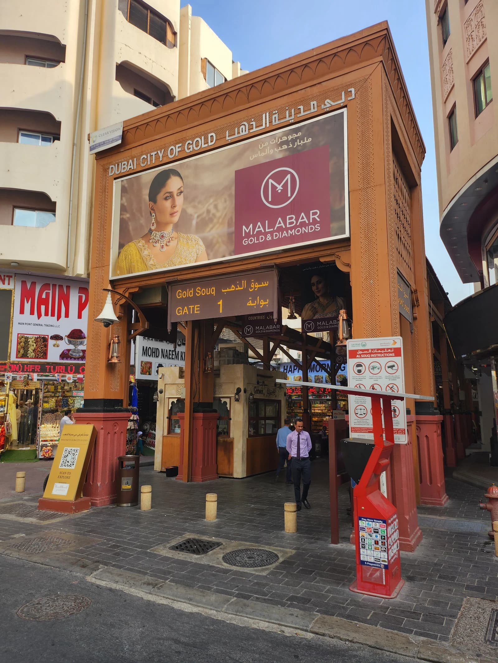 Entrance gate of the Dubai Gold Souk market with shops and advertisements visible.