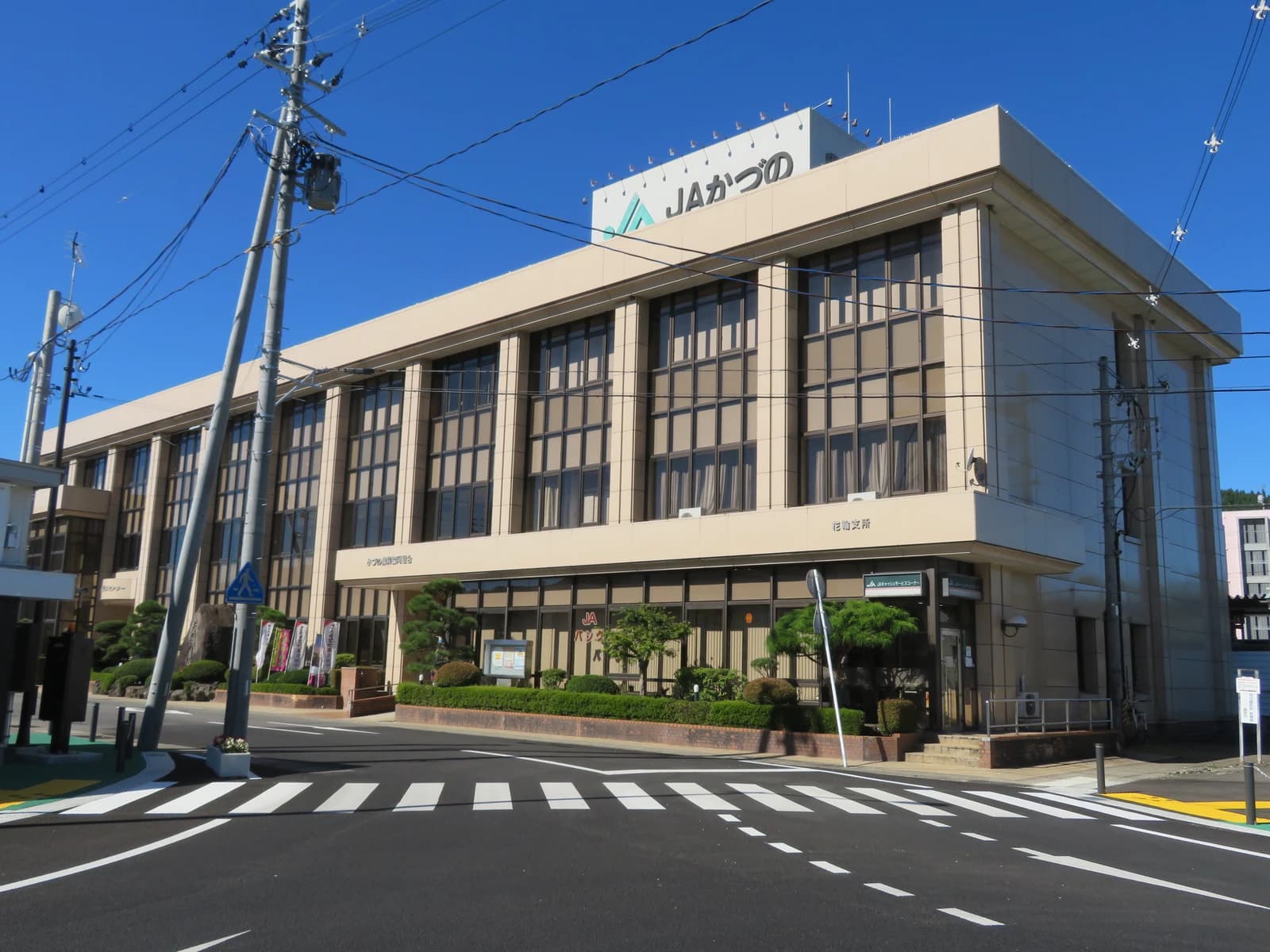 Exterior of the Kazuno agricultural cooperative building under a clear blue sky.