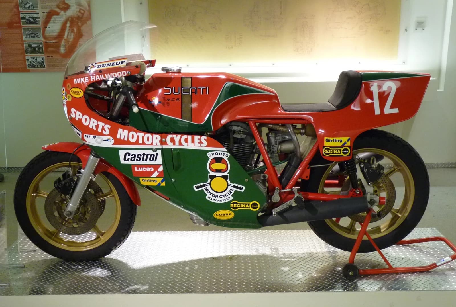 A vintage red and green Ducati 900SS Mike Hailwood Edition motorcycle is displayed indoors.