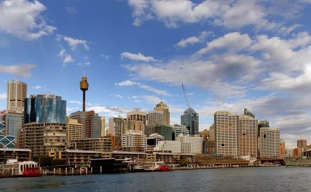 Sydney skyline from Darling Harbour showing multiple high-rise buildings and water in the foreground.