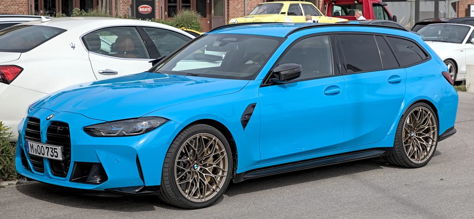 Blue BMW M3 G81 Touring model parked outdoors at Motorworld Munich.