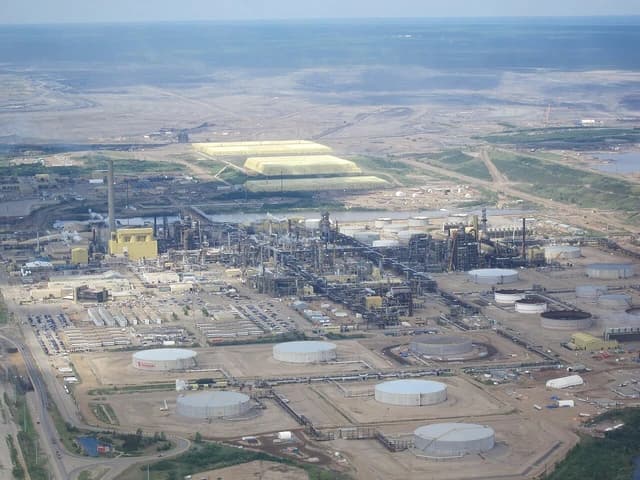 Aerial view of Syncrude oil sands plant with large tanks and industrial buildings.