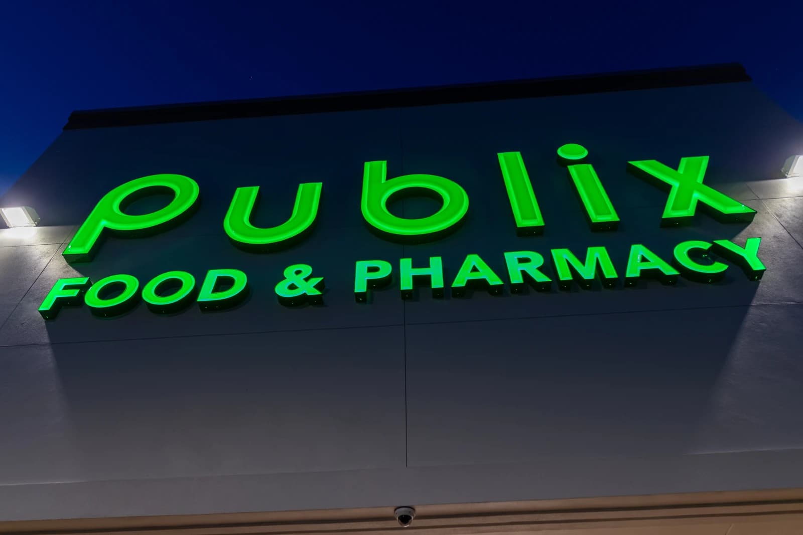 Publix grocery store sign with green lettering illuminated at night.