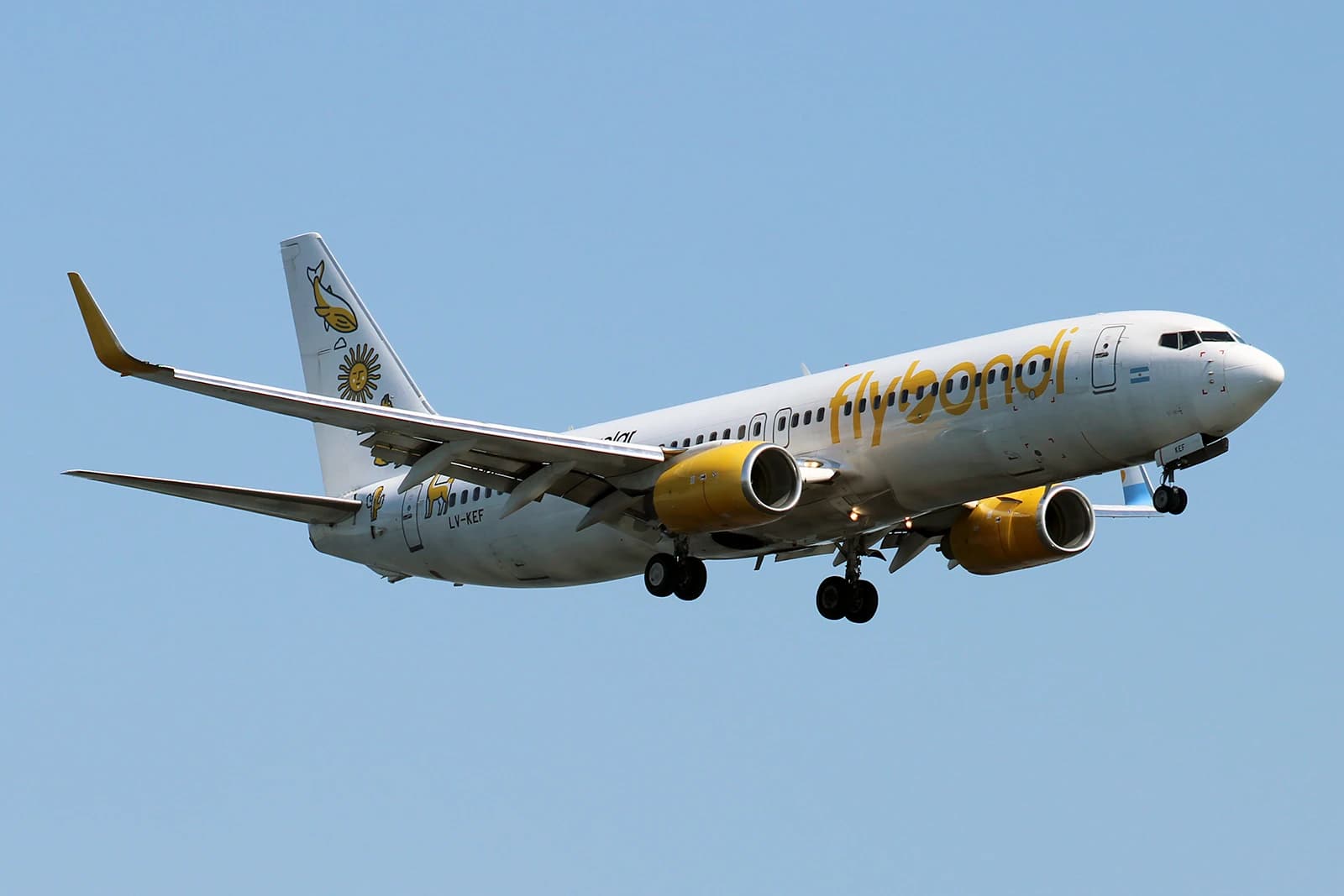 Flybondi Boeing 737 airplane, registration LV-KEF, flying against a blue sky.
