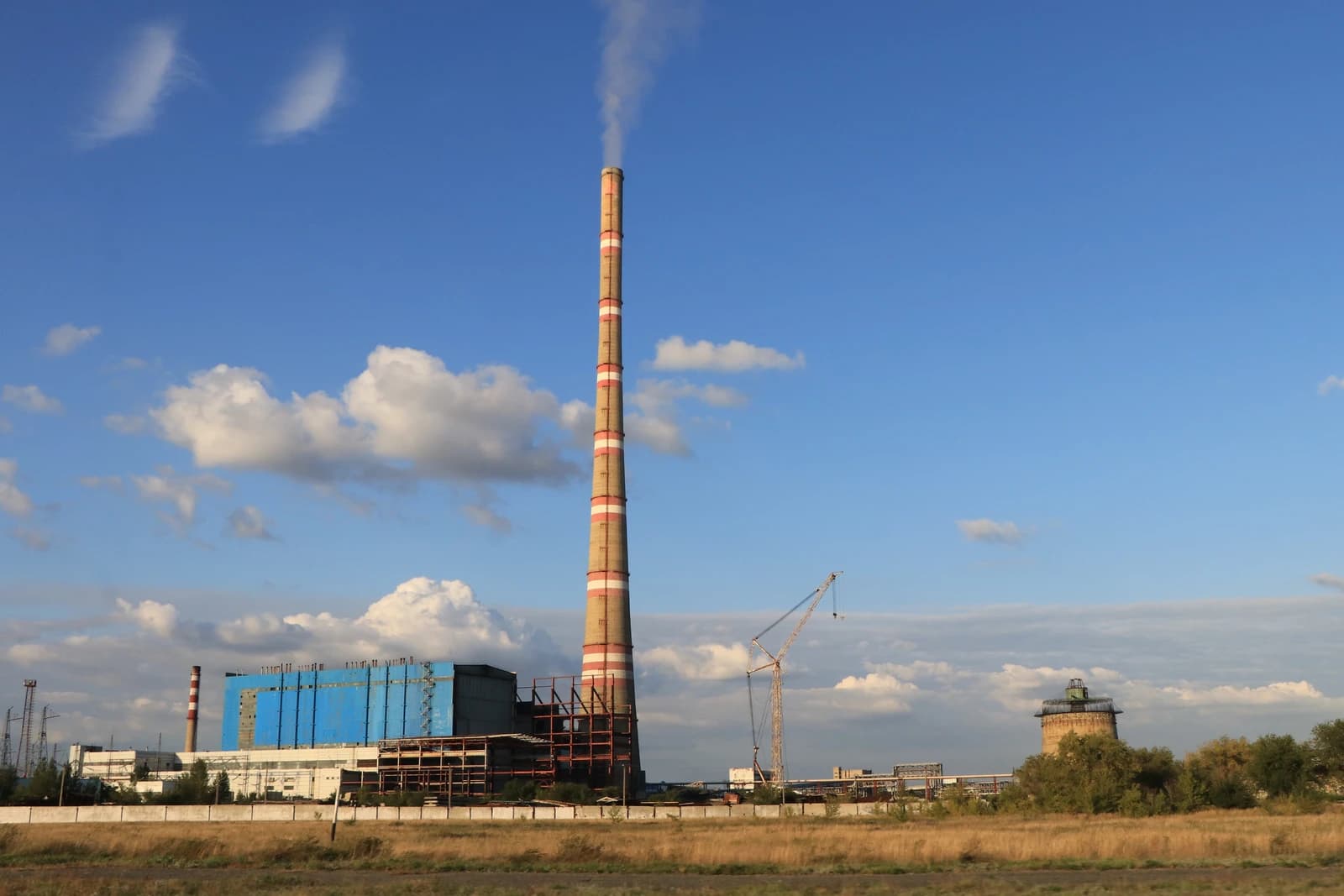 Ekibastuz GRES-2 Power Station with its tall chimney emitting smoke against a blue sky.