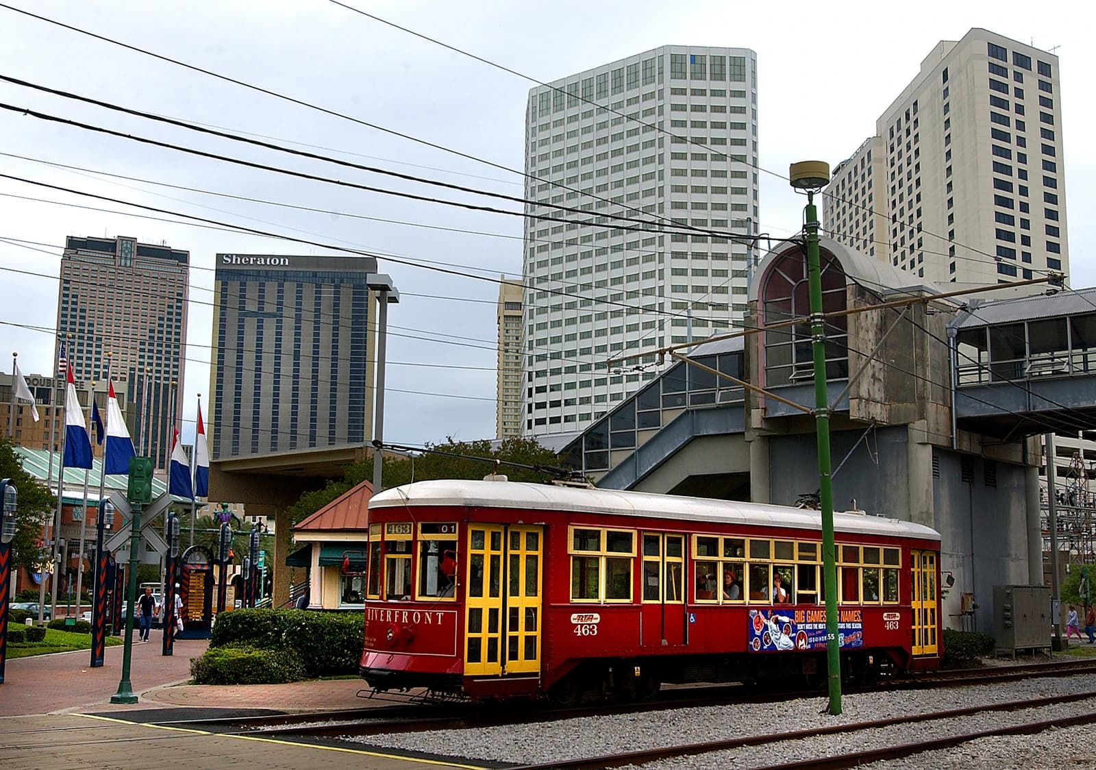 A red New Orleans streetcar with yellow doors travels on tracks in the city.