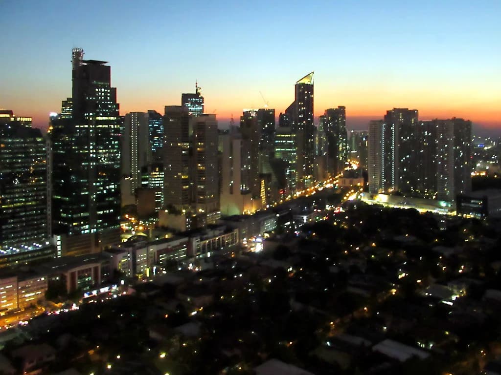 Makati Central Business District skyline at night, showing numerous illuminated buildings.