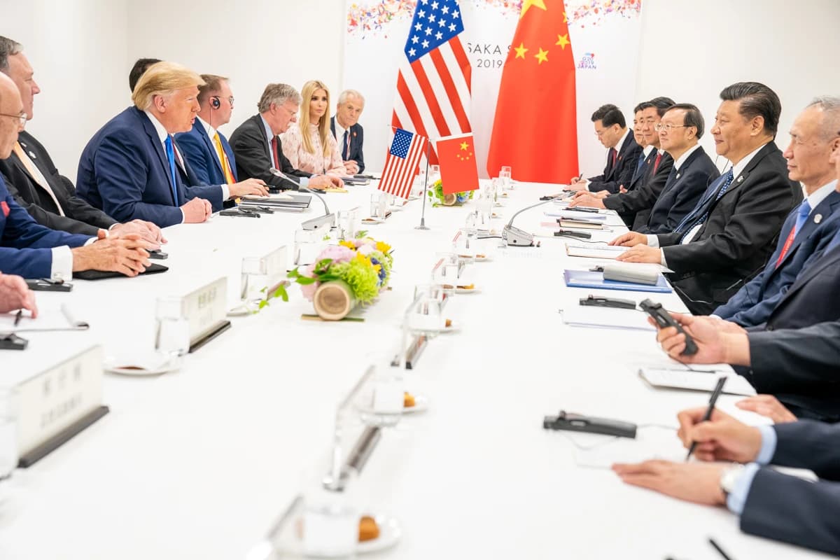 Donald Trump and Xi Jinping seated across from each other at a long table with their respective delegations.