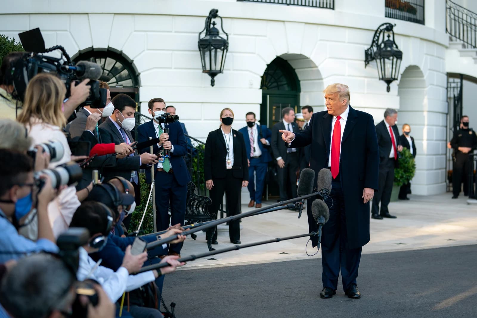 President Trump addressing reporters and photographers outside the White House, pointing a finger.