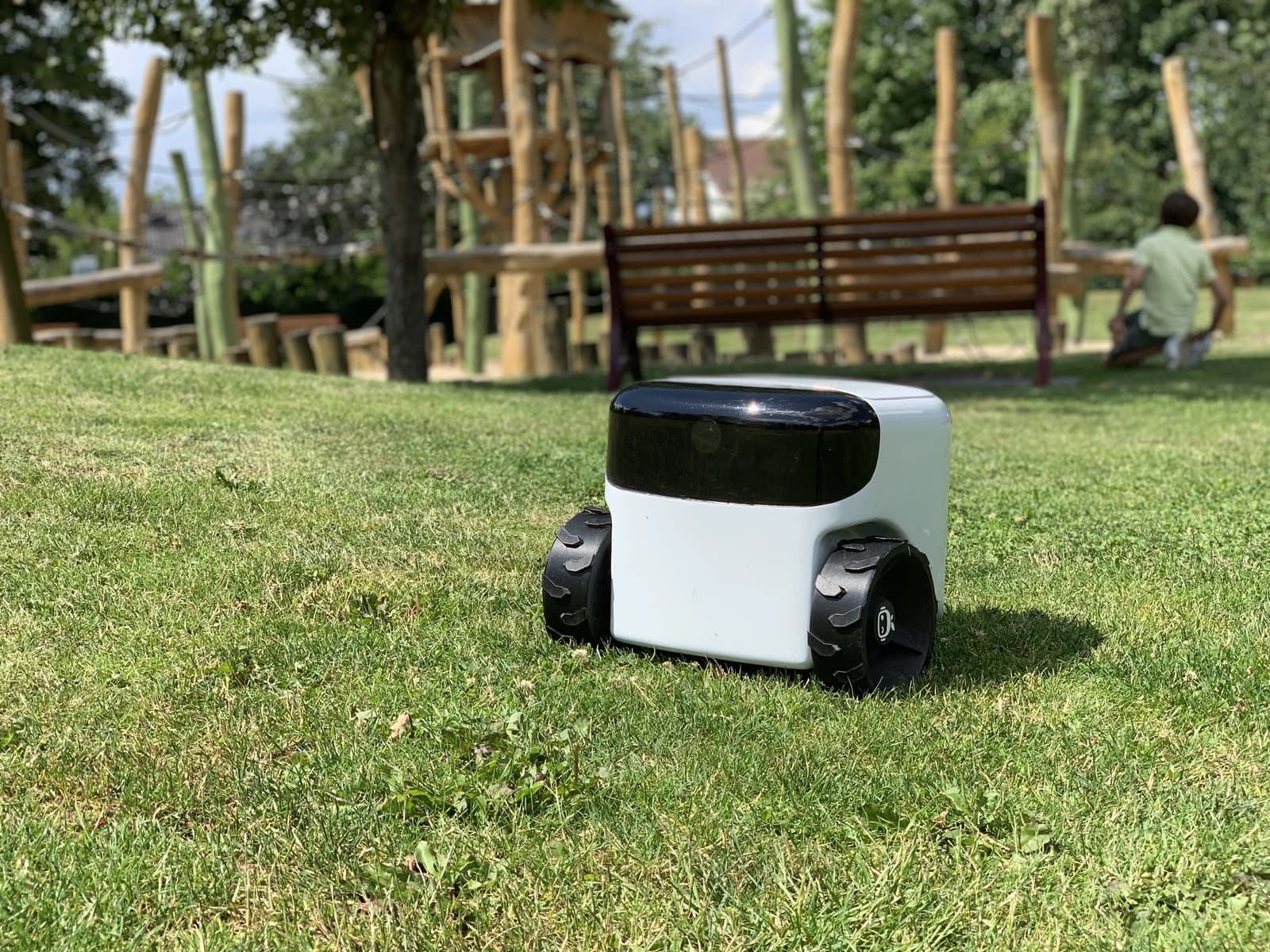 Toadi robotic lawn mower on green grass in a park setting.