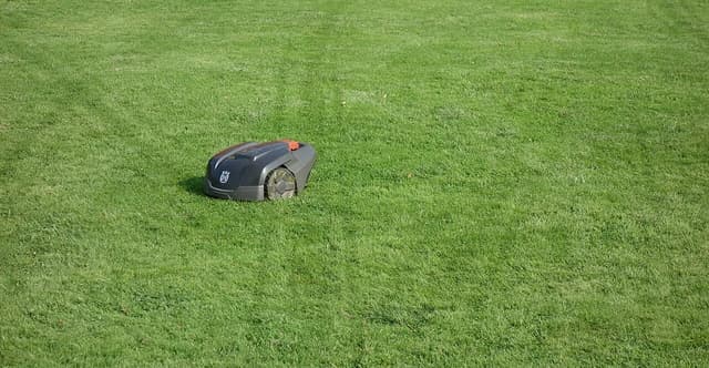 Husqvarna Automower 308 robot lawn mower on a green lawn with visible track marks.