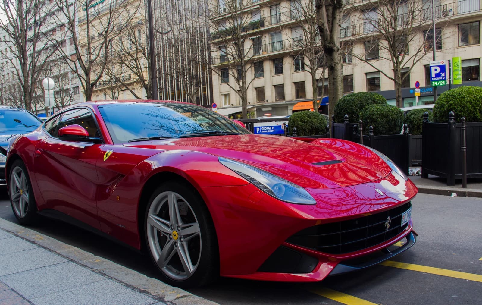 Red Ferrari F12 Berlinetta sports car parked on a city street.