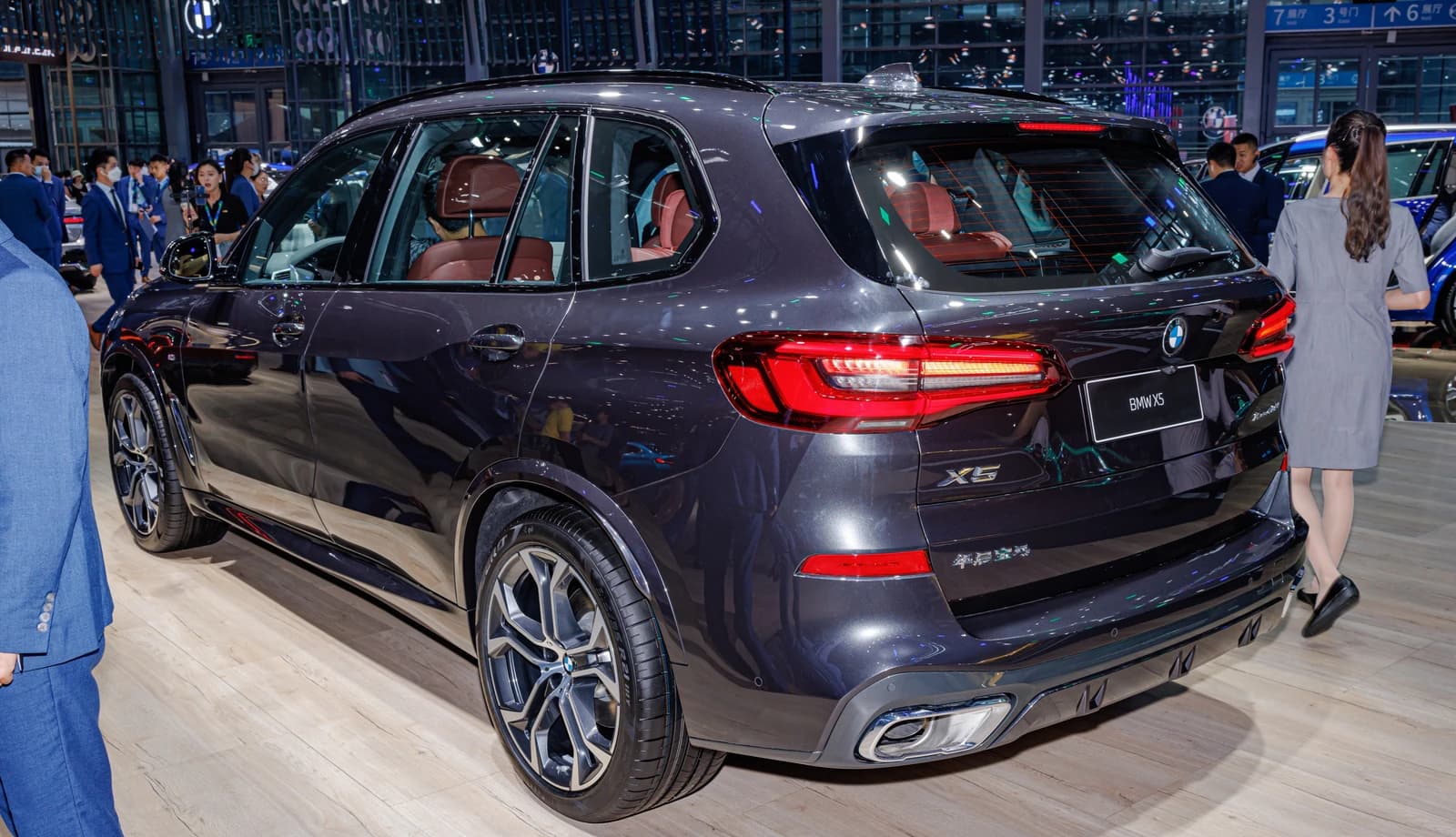 Dark grey BMW X5 LWB (G05) displayed on a wooden floor at an auto show.