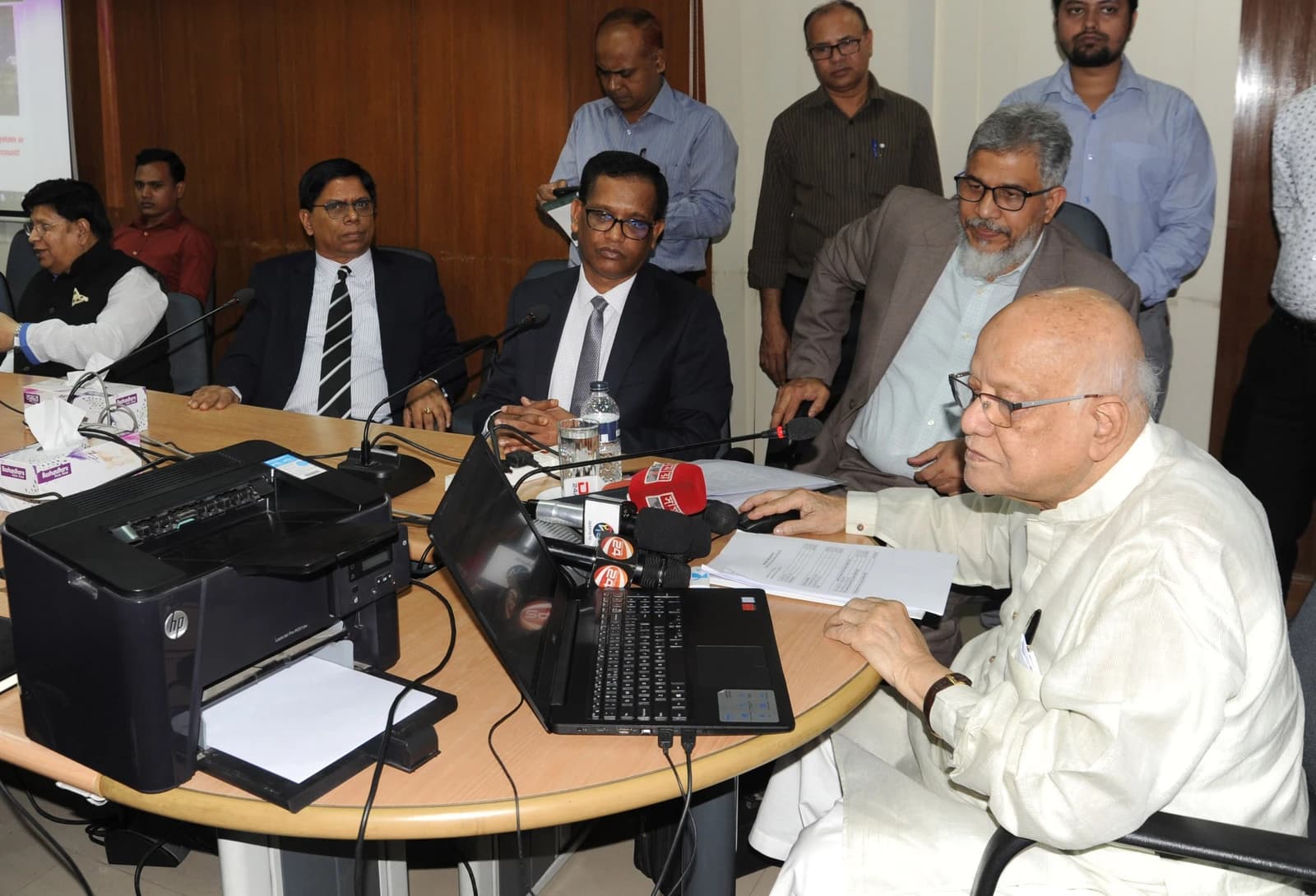 Finance Minister Abul Mal Abdul Muhith, wearing glasses, sits at a desk with a laptop.