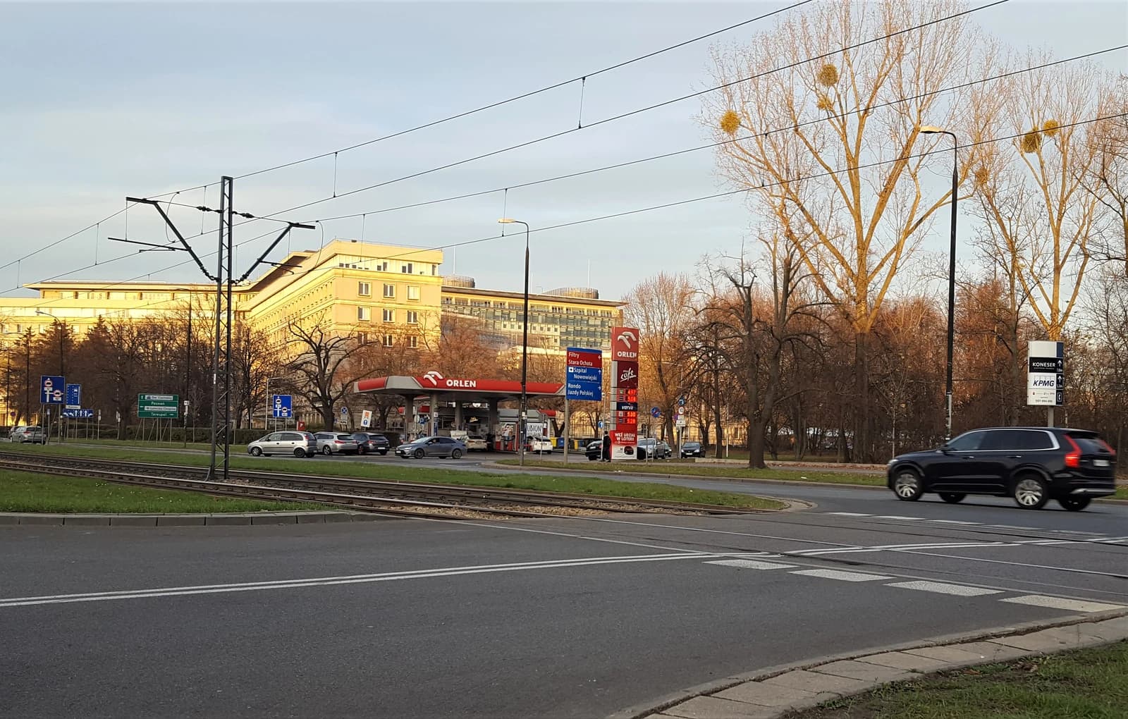 Orlen petrol station in Warsaw with cars on the road and buildings behind.