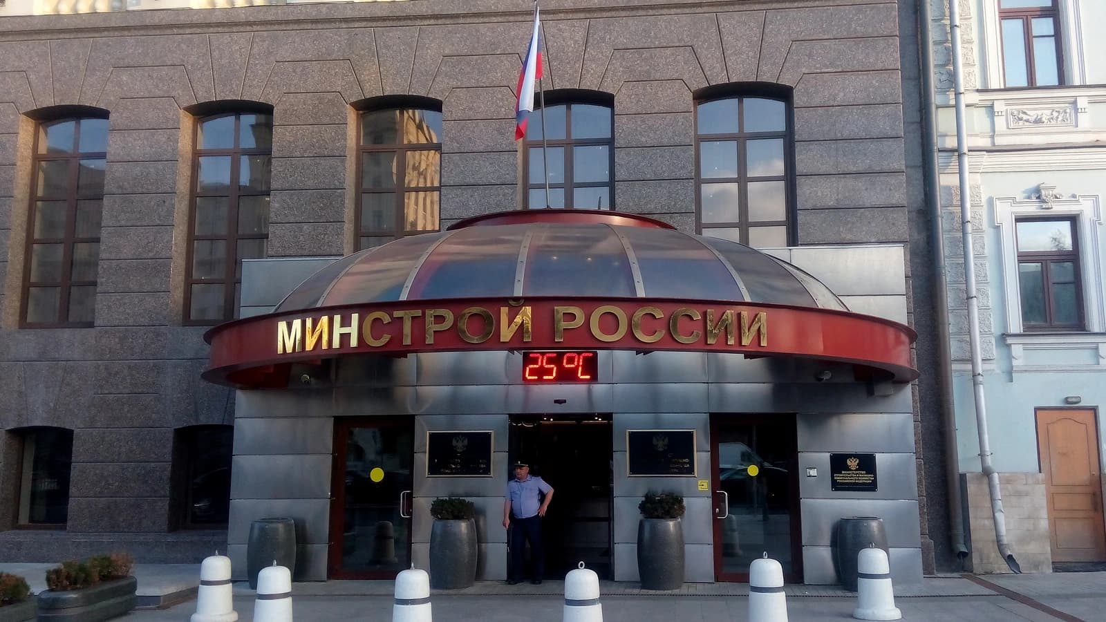 Entrance to the Minstroy RF building with a security guard standing at the doorway.