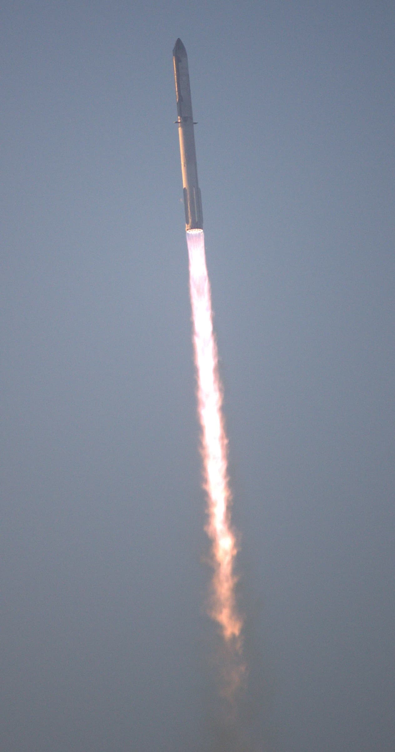 SpaceX Starship rocket launching with bright orange exhaust plumes.