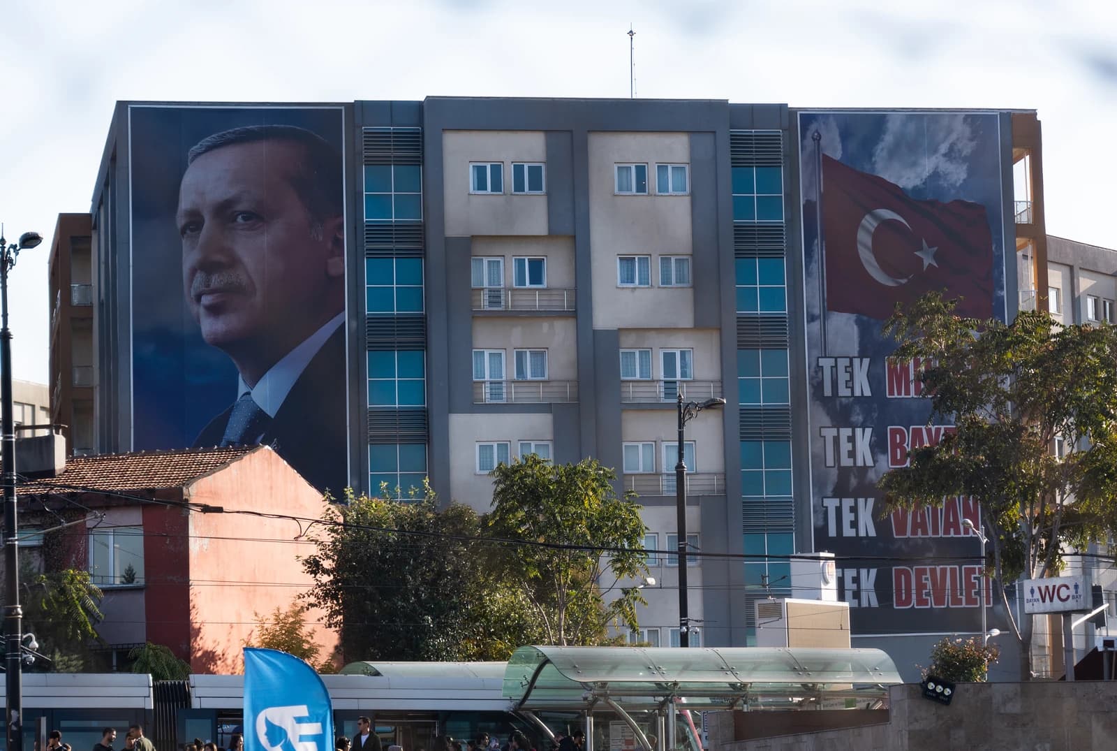 A large mural of Turkish President Recep Tayyip Erdoğan is displayed on the side of a building.
