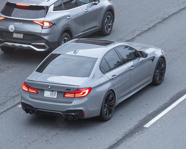 Grey BMW M5 F90 sedan driving on a road in the Washington DC metro area.