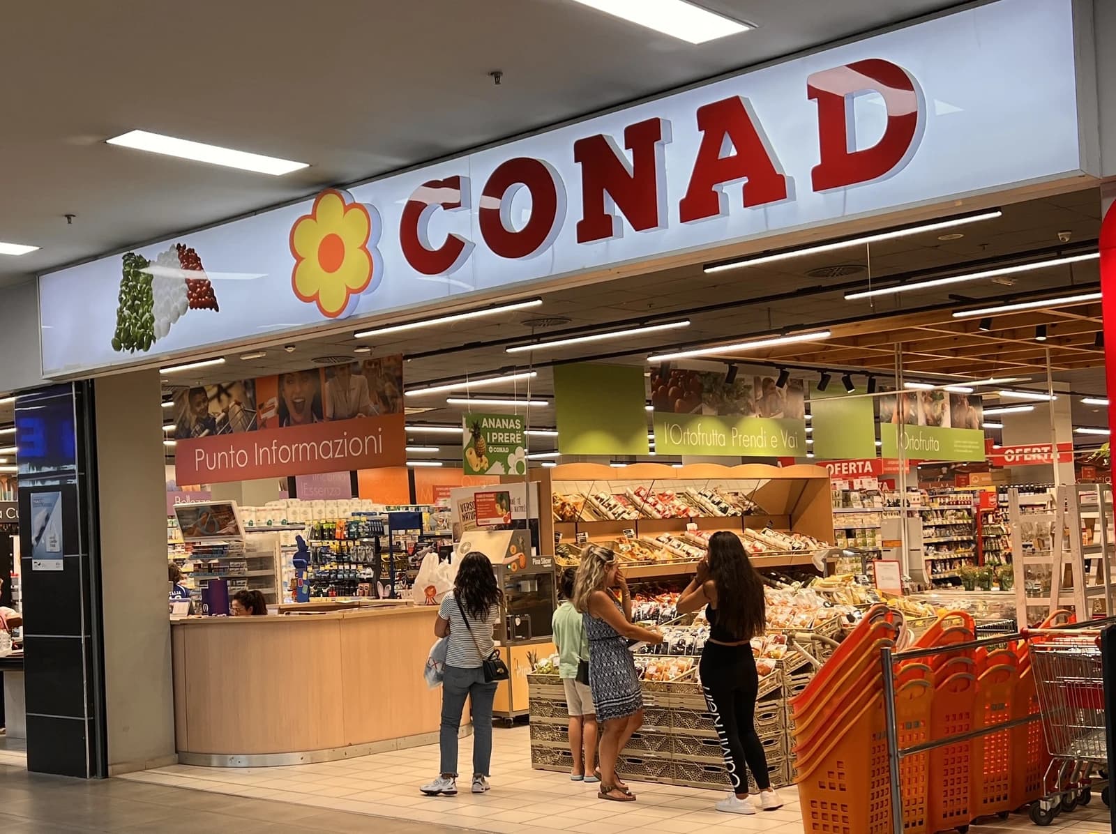 Entrance of a Conad supermarket in Tirana, Albania, with shoppers inside.