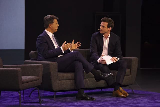 Harald Krüger and Aljoscha Höhn speaking on a stage at an event.