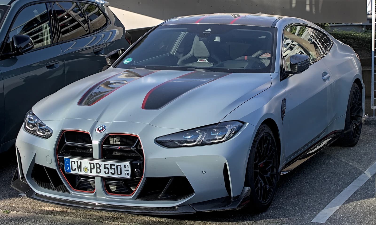 Gray BMW M4 CSL car with red accents on the hood and grille.