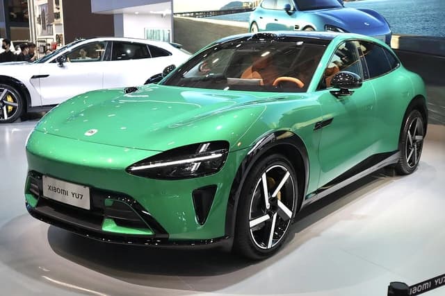 Green Xiaomi YU7 electric car parked inside a showroom with other vehicles.