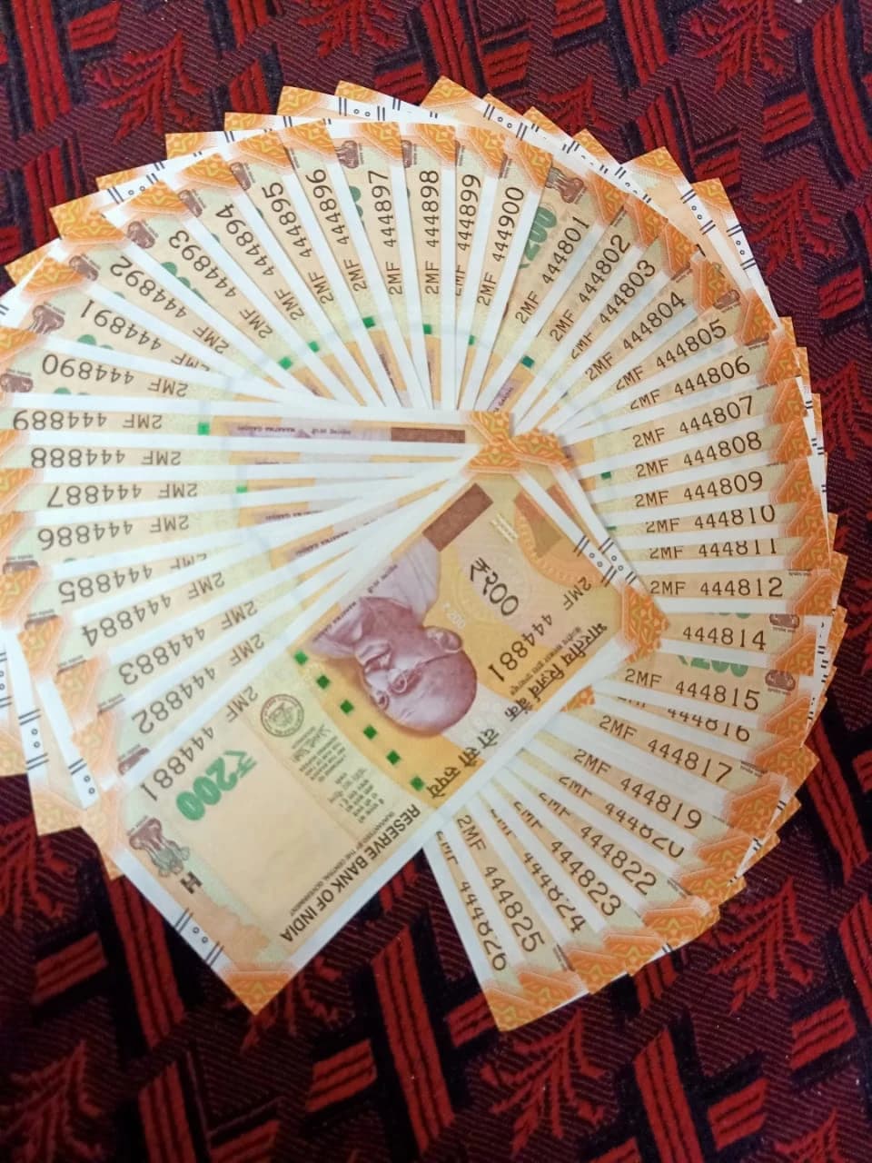 Indian two hundred rupee banknotes fanned out on a patterned surface.