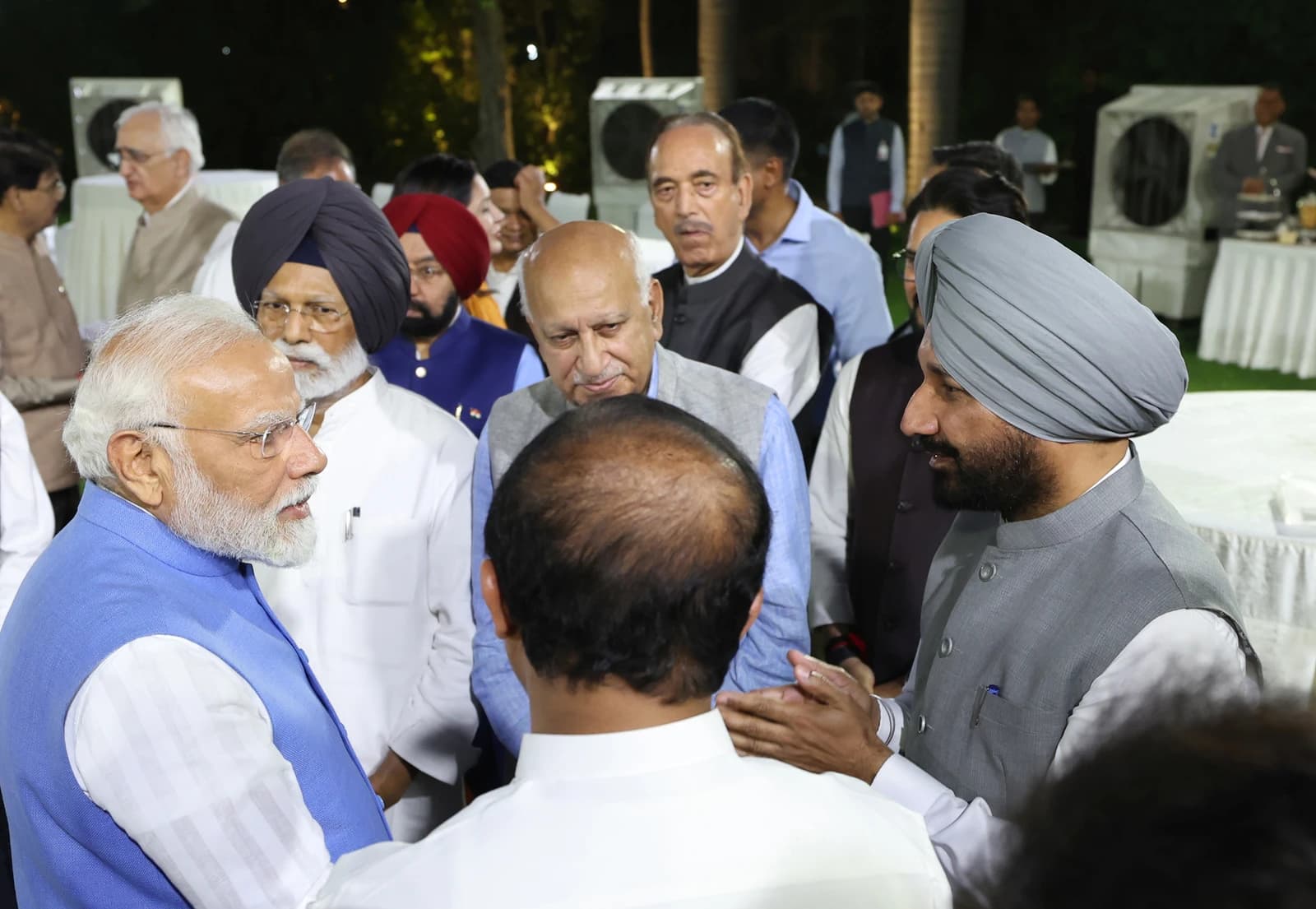 Prime Minister Narendra Modi speaking with people in a group setting.