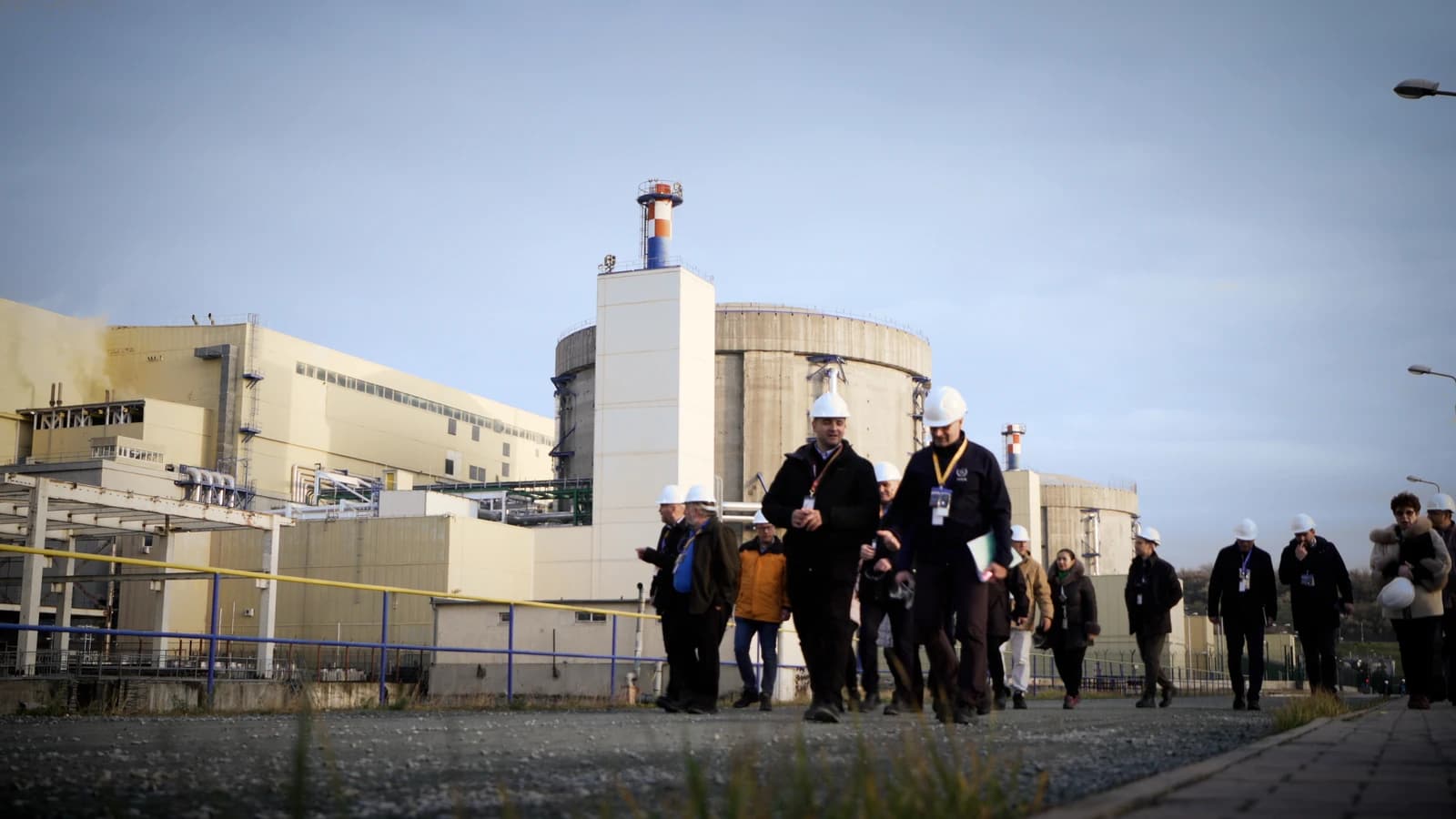 People in hard hats walking past buildings at the Cernavodă Nuclear Power Plant.