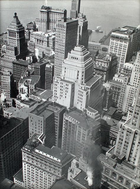 Aerial view of financial district rooftops in Manhattan, New York, with a river in the background.