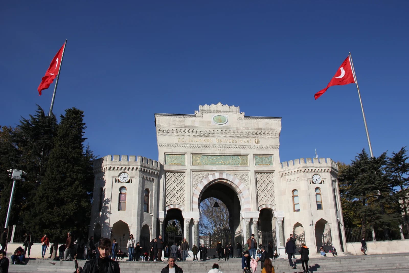 Main gate of Istanbul University with Turkish flags flying on either side.